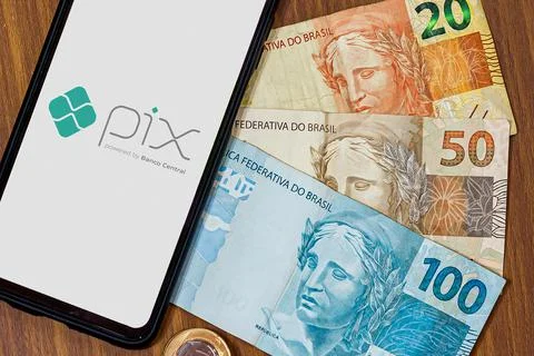 Pix logo on smartphone screen with multiple coins around Stock Photos