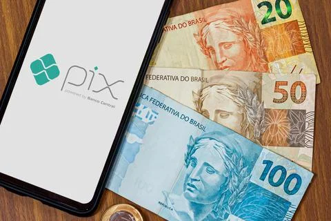Pix logo on smartphone screen with multiple coins around Stock Photos