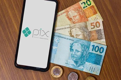 Pix logo on smartphone screen with multiple coins around Stock Photos