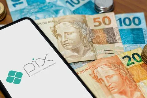 Pix logo on smartphone screen with multiple coins around Stock Photos