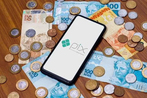 Pix logo on smartphone screen with multiple coins around Stock Photos