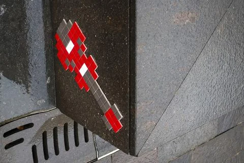 A pixelated spaceship key crafted from small tiles adorns a dark stone surf.. Fotos de archivo