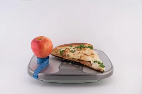 Pizza and apple on scales Stock Photos