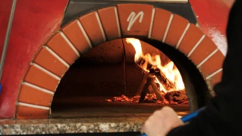 Pizza baker placing multiple pizzas in brick oven Stock Footage 86902063