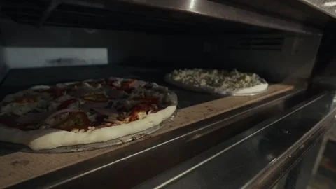 Pizza baking process in commercial oven with two pizzas visible, one with Stock Footage 332736641
