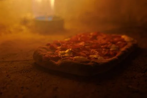 Pizza baking with visible flame in rustic oven Stock Photos