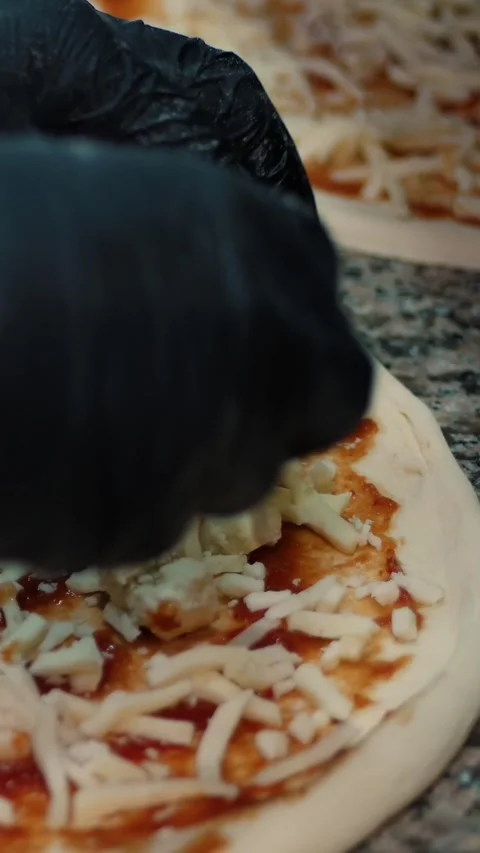 Pizza being prepared in the restaurant kitchen. The chef sprinkles Italian pizza Stock Footage 314115480