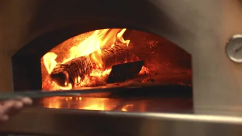Pizza being turned inside a dome-shaped wood-burning pizza oven Stock Footage 203876973