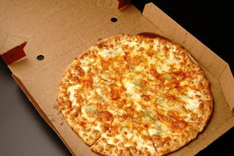 Pizza in a box on a black background. Stock Photos