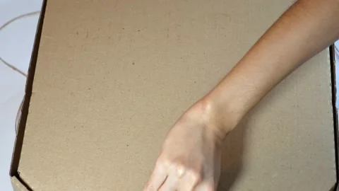 Pizza in a box close-up.A hand opens a brown pizza box. Stock Footage 221990711
