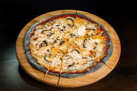 Pizza with champignons and chicken breast on black dough. Фото