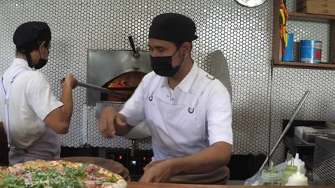 Pizza chef adding grates cheese on freshly baked pizza and puts it on a wooden Stock Footage 150004667