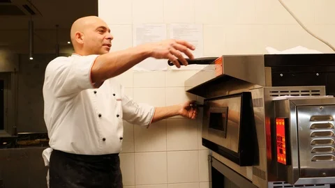 Pizza chef checking on gluten free pizza in the oven  Stock Footage 86902281