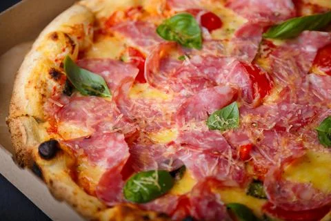 Pizza closeup texture, food pattern background. Ham, tomatoes, green basil Foto stock