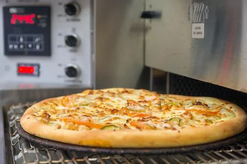 The pizza is cooked in an automatic oven. Stock Photos