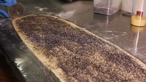 A pizza cutter cut thin strips of dough with poppy seeds Stock-Footage 106484628