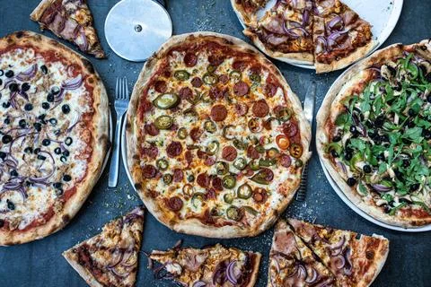 Pizza dinner. Flat lay of various types of Italian pizza on rustic table, t.. Stock Photos