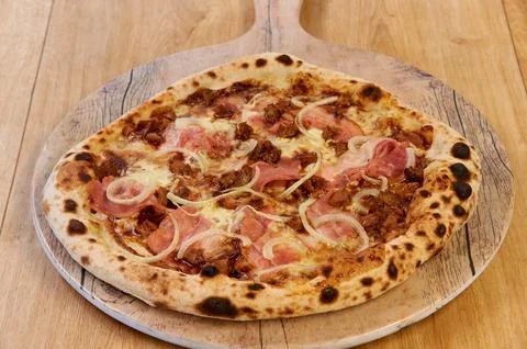 A pizza with ham and onions on top Stock Photos