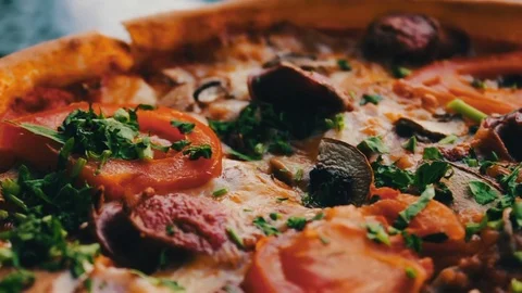 Pizza with hunting sausage, tomato, herbs and cheese close up view Stock Footage