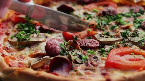 Pizza with hunting sausage, tomato, herbs and cheese close up view Stock Footage
