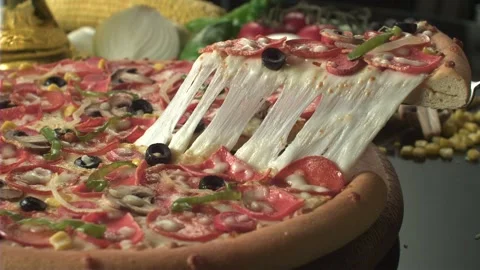 A pizza lifter takes out a slice from a pizza that has various of toppings Stock Footage 161525832