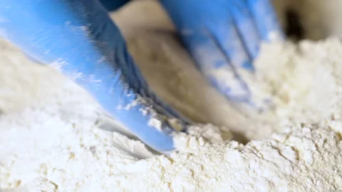 Pizza maker with blue gloves stretching hand slapping dough ball in flour Stock Footage 130827916