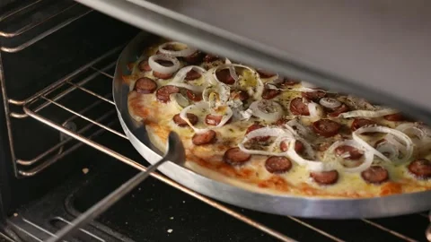 Pizza maker checks the pizza inside the oven. Chef rotates the pizza with spoon Stock Footage 338040131