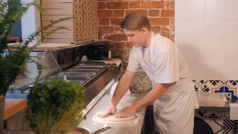 Pizza maker forms thin dough standing behind cafe counter Stock-Footage 126951951