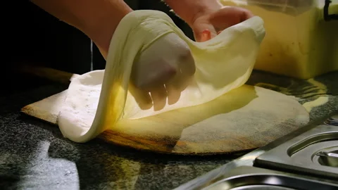 Pizza maker lays thin dough sheet on wooden peel board Stock Footage 325069723