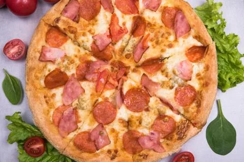 Pizza pepperoni close-up on the table with tomatoes Stock Photos