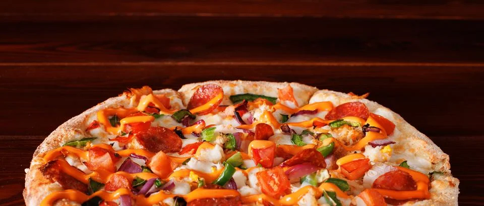Pizza with pepperoni, pepper, onion and sauce lies on a wooden table made of  Stock Photos
