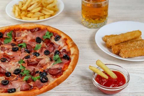 Pizza on a platter close-up on a table with ketchup, juice, sauce and fries on a Stock Photos