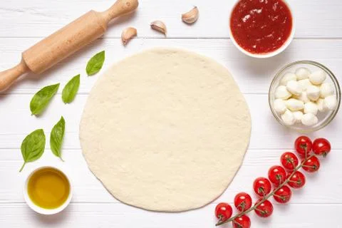 Pizza preparation. Baking ingredients on the kitchen table: rolled dough Stock Photos