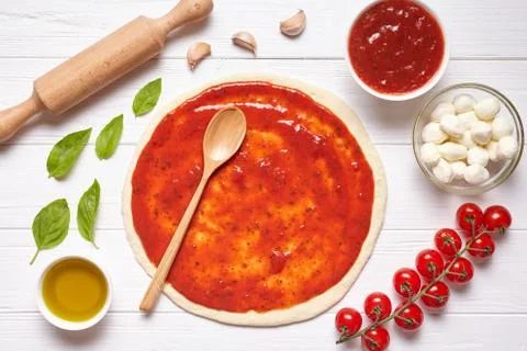 Pizza preparation. Baking ingredients on the kitchen table: rolled dough with Stock Photos