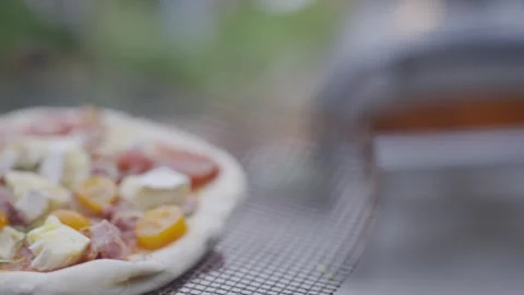 A pizza is sitting on a table next to a pizza oven Stock Footage 297842848