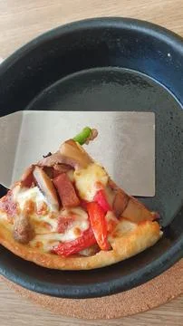 Pizza slice in black pan Stock Photos