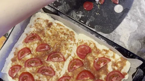 A pizza with tomato slices on it is being prepared 스톡 동영상 282298129