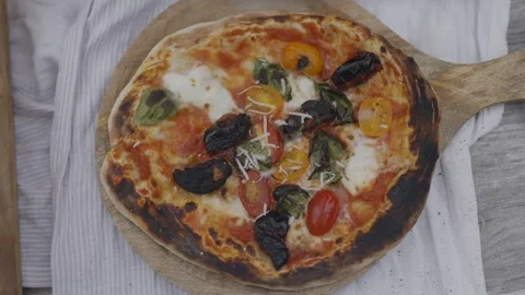 A pizza with tomatoes and basil on top of a wooden board Stock Footage 297842486
