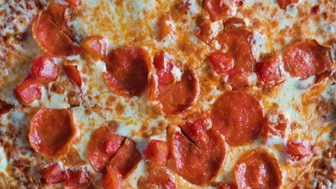 The pizza is topped with crispy pepperoni and diced tomatoes arranged neatly on 動画素材 338290137