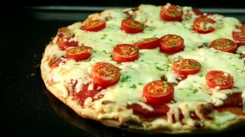 A pizza topped with mozzarella and cherry tomatoes baking in the oven Video stock 24673325