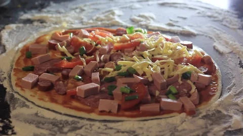 Pizza with toppings for cooking on a cutting table. Adding cheese. Stock Footage 129554738