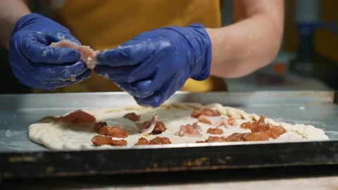 The pizzaiolo chef is preparing pizza in the bakery. The pizzaiolo puts meat and Stock Footage 261336990