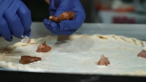 The pizzaiolo chef is preparing pizza in the bakery. The pizzaiolo puts meat and Stock Footage 261337173