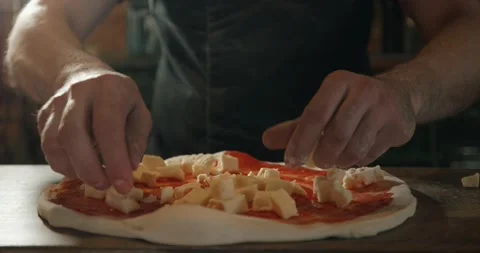Pizzaiolo putting cubes of cheese on raw pizza with tomato sauce Stock Footage 201467803