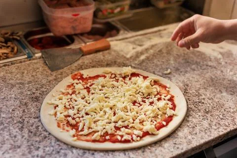 Pizzeria chef unrecognizable hands preparing a fresh pizza. professional kitchen Stock Photos