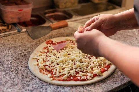 Pizzeria chef unrecognizable hands preparing a fresh pizza. professional kitchen Stock Photos