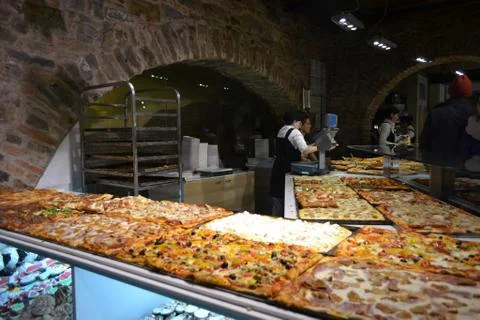 Pizzeria shop with the counter full of different Italian pizzas. Stock Photos