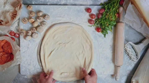 Pizzeria worker rolls dough pointwise with fingers in flour and turns over Stock Footage 151467583