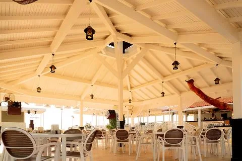 Place for dining is set up by sea with rows of empty tables  chairs. Sunlight Foto stock