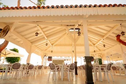 Place for dining is set up by sea with rows of empty tables  chairs. Sunlight Foto stock
